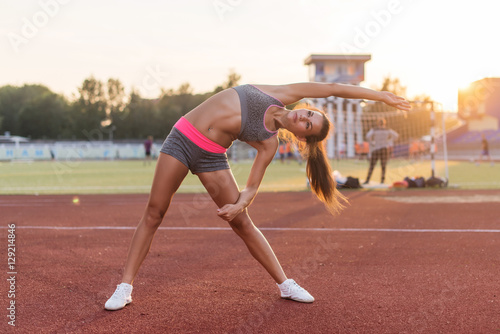 Fit woman doing side bend stretching exercise warming up.