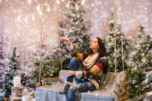 Young woman catching a snowflake while sitting on a swing with a © kolotype