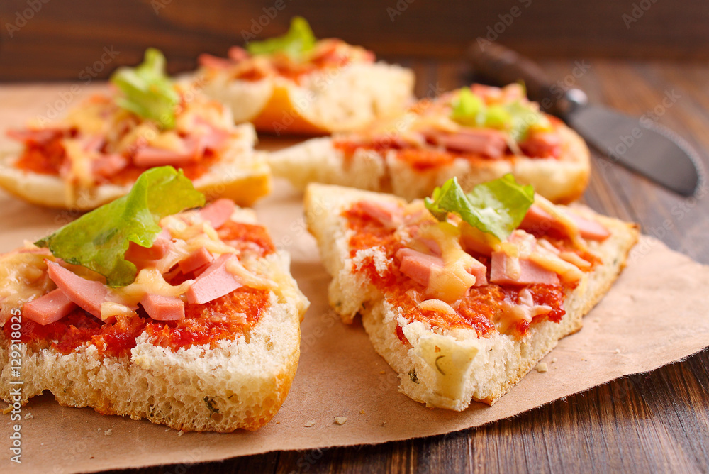 Pizza slices on parchment on wooden background Pizza slices on parchment on wooden background