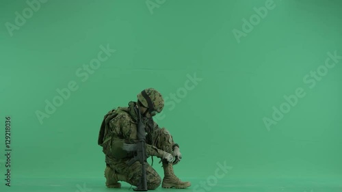 serviceman tying shoelaces at green screen photo