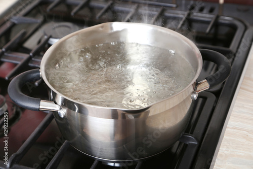 Water boiling into saucepan on the gas stove