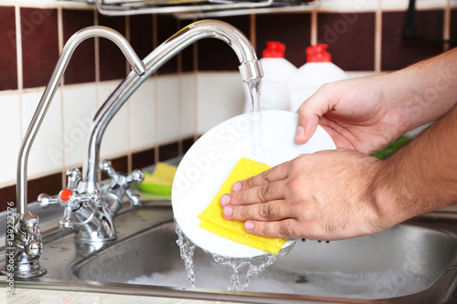 Male hands with sponge washing dish