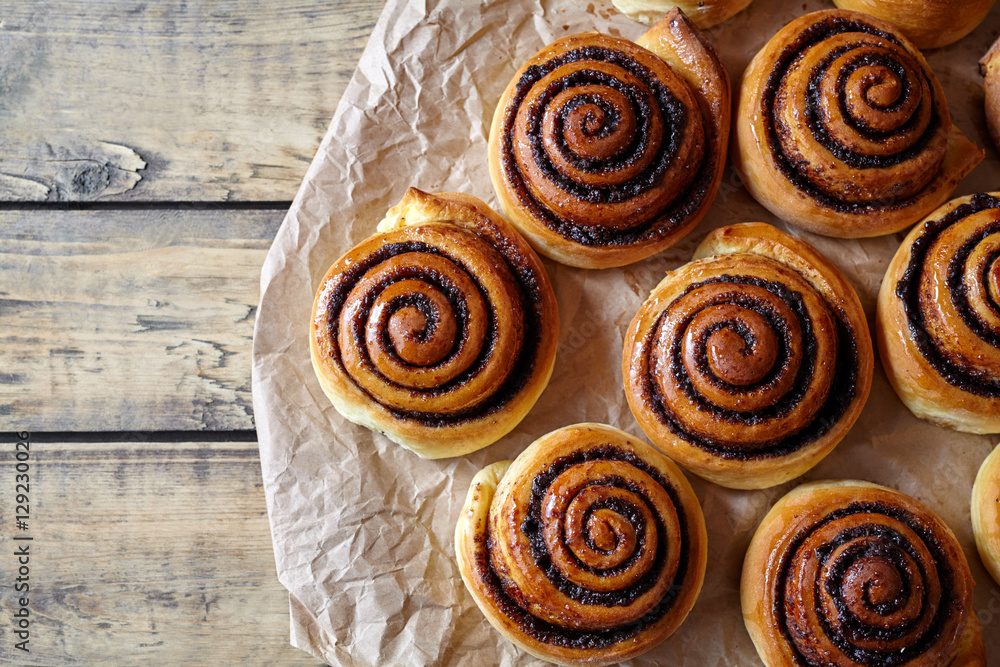 Sweet Homemade christmas baking. Cinnamon rolls buns with cocoa filling on parchment paper. Kanelbulle swedish dessert. Festive decoration with pine cones and Christmas tree