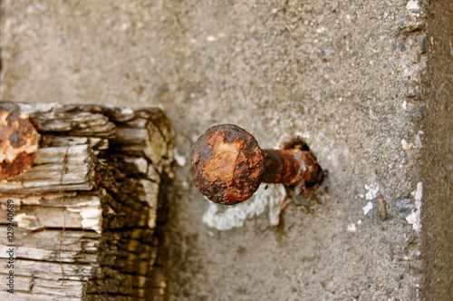 Old rusty nail in the concrete construction and abandoned piece of wood