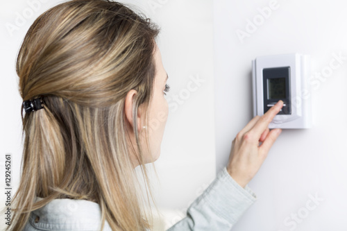 woman set the thermostat at house.