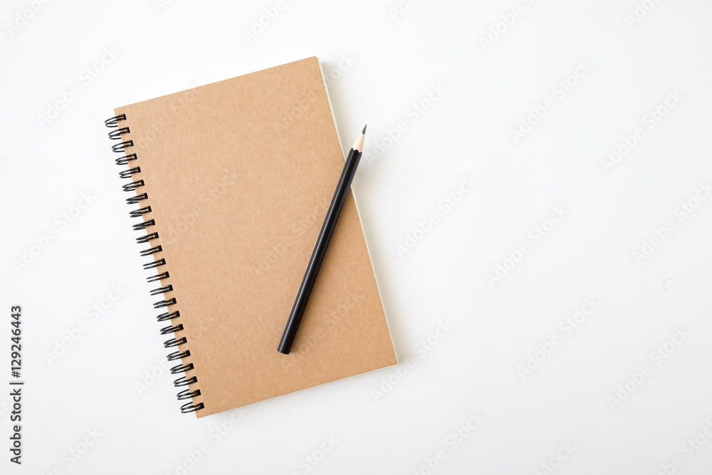 Top view of closed spiral blank craft paper cover notebook with pencil on white desk background - obrazy, fototapety, plakaty 