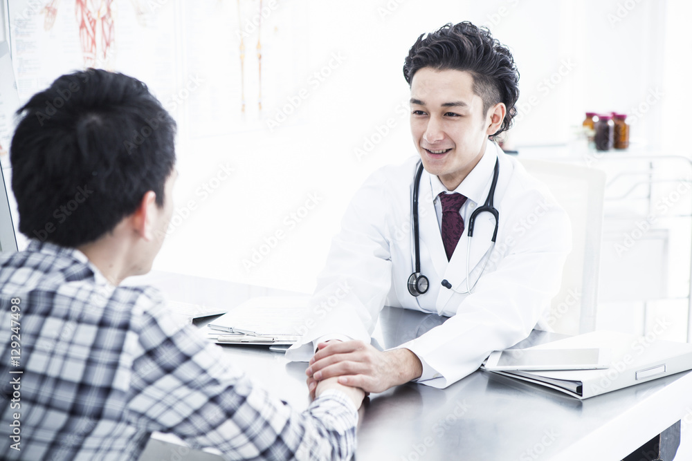 The doctor encourages the patient in the examination room The doctor encourages the patient in the examination room