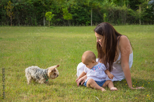 Happy mother and child with dog on grass in park