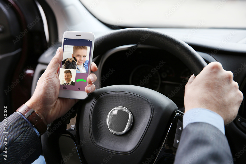 Man video conferencing on smartphone in car.  Modern technology concept.