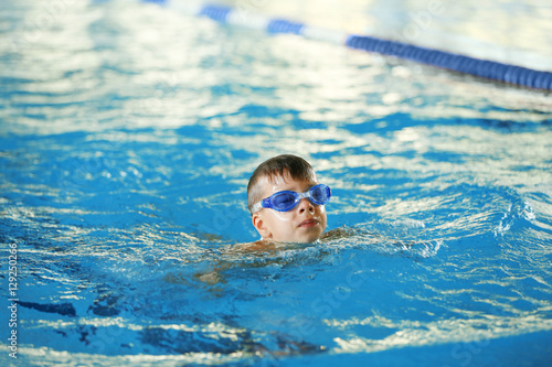 Cute boy training in sport swimming pool