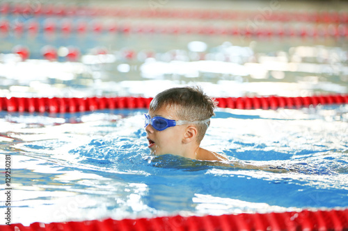 Cute boy training in sport swimming pool