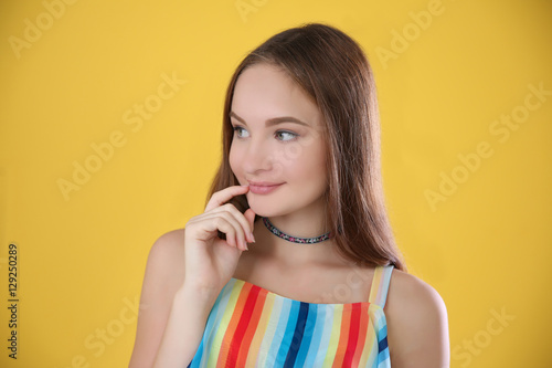Portrait of beautiful teenage girl on yellow background