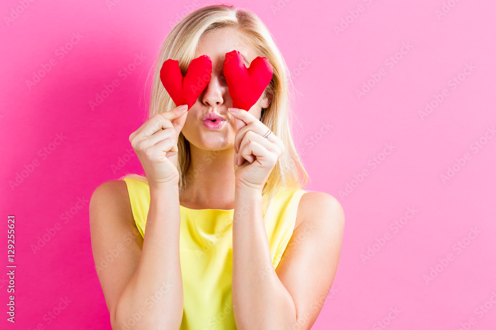 Happy young woman holding heart cushions Happy young woman holding heart cushions