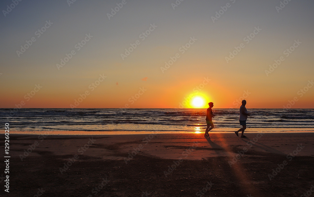 People are running at the sunrise on the beach. Silhouette. Italian coast. Emilia Romagna. Italy