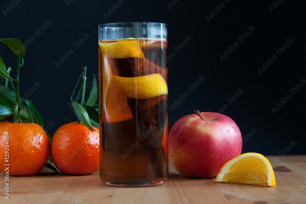 Glass with Seasonal warming drink.Cinnamon,lemon zest and some fruits.