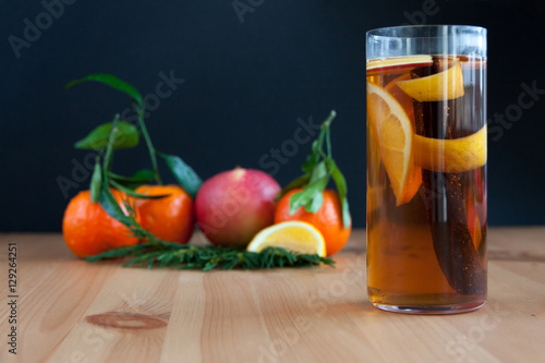 Glass with Seasonal warming drink.Cinnamon,lemon zest and some fruits.