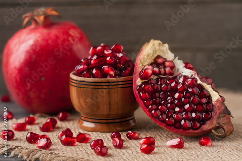 pomegranate and grains in the bowl on the old wooden board with sackcloth