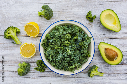 Fresh kale leaves and avocado on a wooden table.The raw ingredients for a salad. 