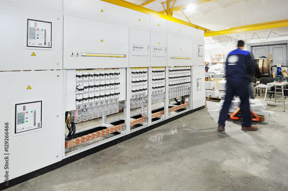 Fototapeta premium Worker in overalls carries the details along the rack of electri