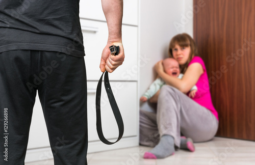 Bild auf Leinwand Man with a belt is abusing his wife and baby - domestic violence