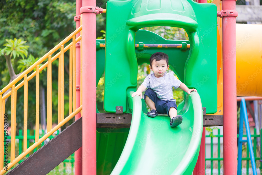 Little Asian kid playing slide at the playground