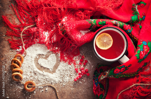 Hot fruit tea with lemon on wooden background with bagels, Slavic headscarf and snow. view from above photo