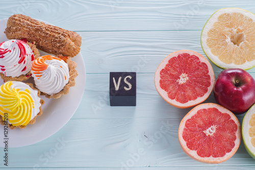 Choosing between Fruits and Sweets. Healthy versus unhealthy food. Weight Loss. Unhealthy tempting cakes and healthy fruits