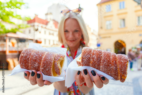 Fotografía Young female tourist with traditional czech dessert called trdelnik in Prague