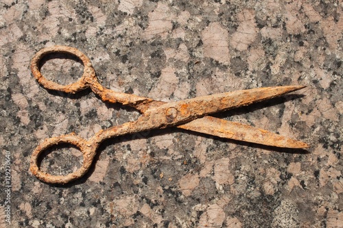 Old rusty scissors on a granite countertop. Old tool tailor. 