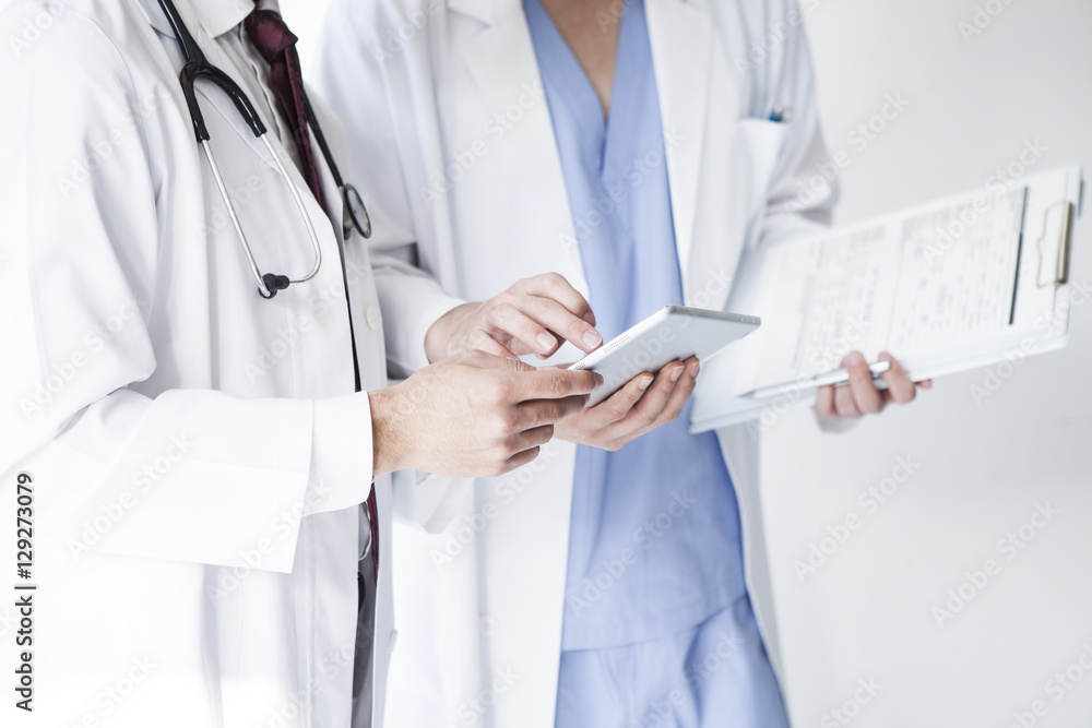 Doctors are talking while watching electronic tablets at a hospital Doctors are talking while watching electronic tablets at a hospital