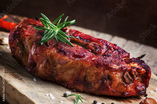 Piece of baked pork with garlic and rosemary, vintage wooden bac