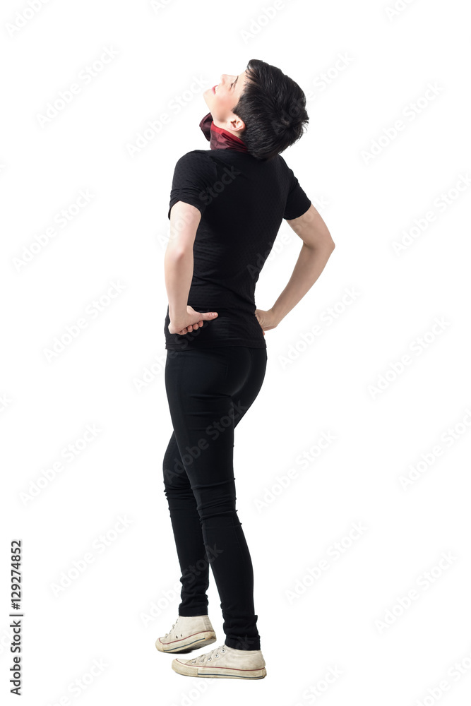 Rear view of young happy woman laughing and looking up with hands on hips. Full body length portrait isolated over gray studio background. Rear view of young happy woman laughing and looking up with hands on hips. Full body length portrait isolated over gray studio background.