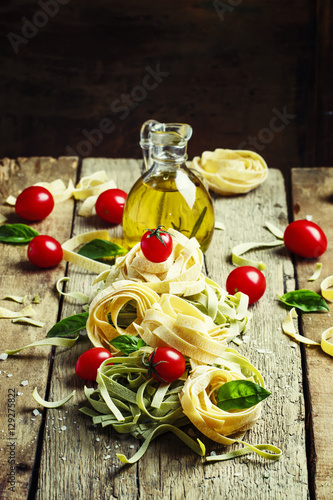 Dried pasta tagliatelle with basil and tomatoes, vintage wooden