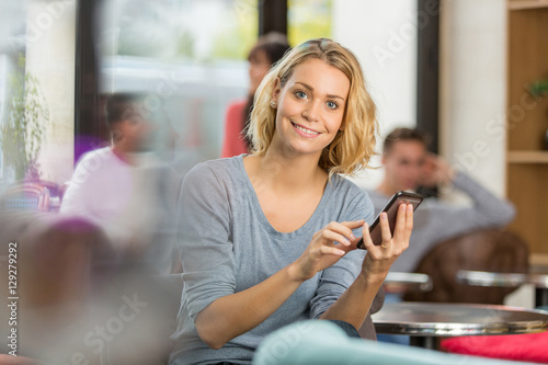 young woman using mobile phone in a fancy cafe