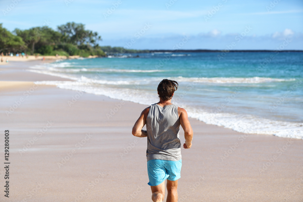 Man athlete running away from behind on beach at sunset. Male runner doing cardio exercise workout on sand with ocean background. Healthy active life on travel destination.