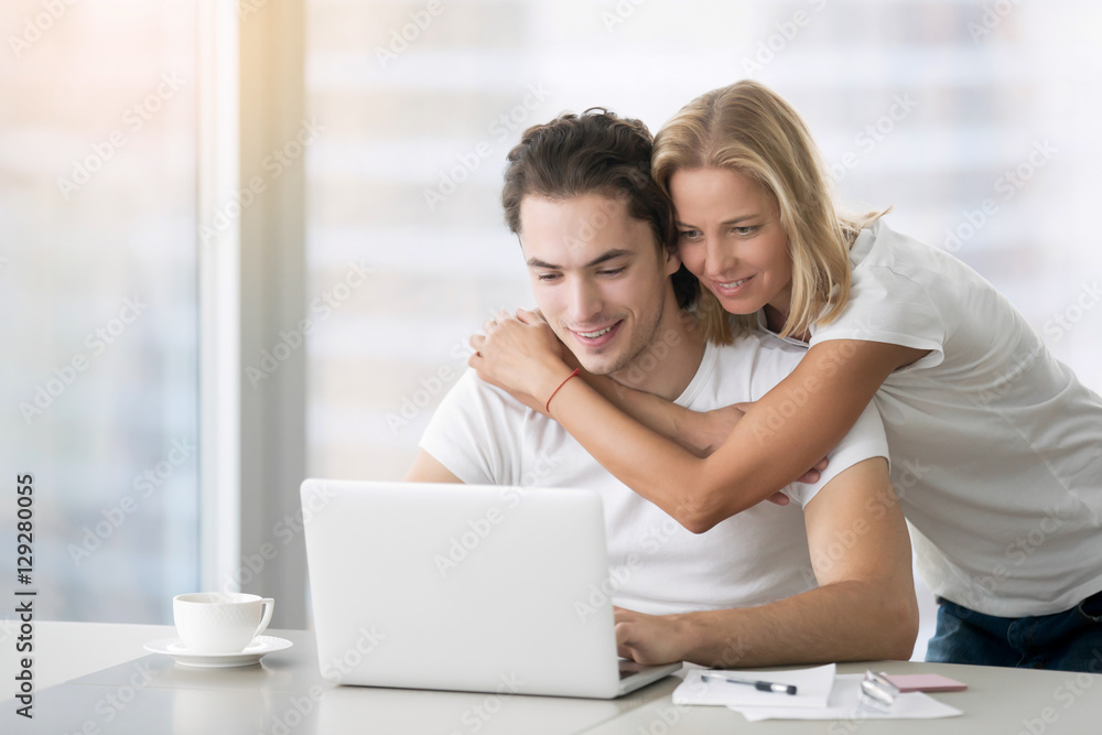 Young happy people looking at laptop, building family financial plan, meal planning for healthy style, wedding ideas, ordering gifts, free online courses to get diploma. Man working in home office Young happy people looking at laptop, building family financial plan, meal planning for healthy style, wedding ideas, ordering gifts, free online courses to get diploma. Man working in home office