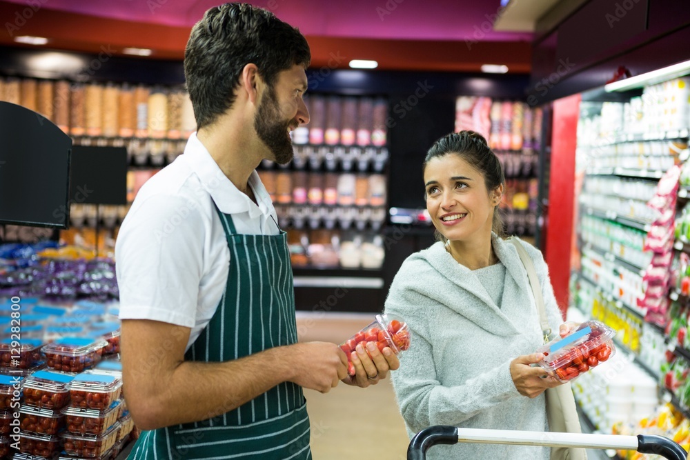 Smiling male staff assisting a woman with grocery shopping