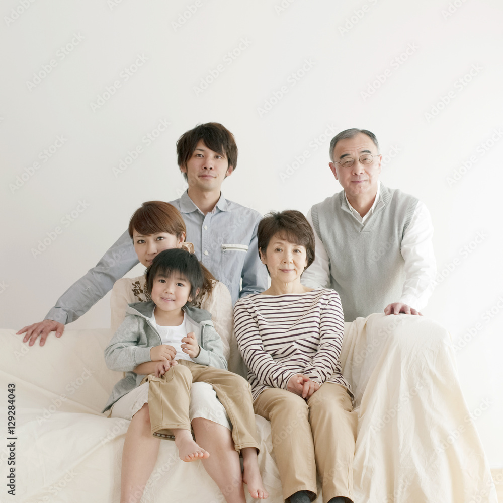 ソファーに座り微笑む3世代家族