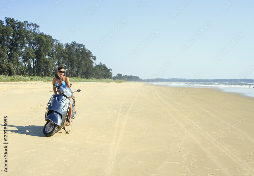Obraz premium Tanned brunette rides on a deserted beach along the ocean at mot