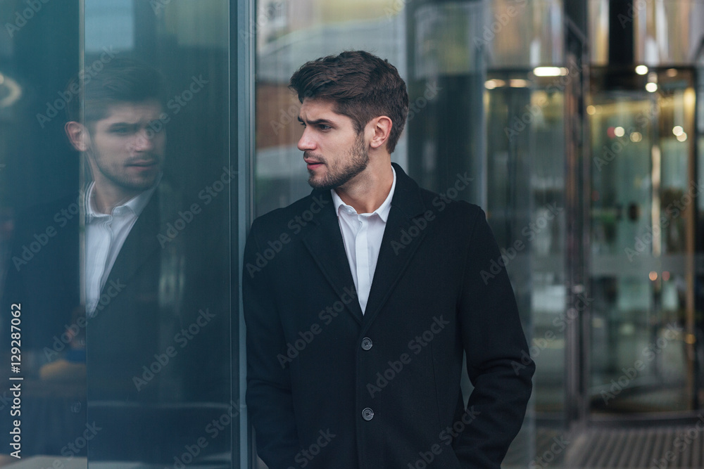 Attractive businessman standing near business center and look as