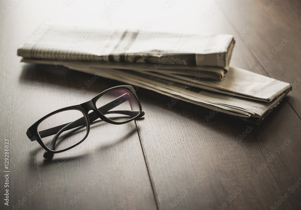 Newspaper and reading glasses on business desk business newspape Newspaper and reading glasses on business desk business newspape