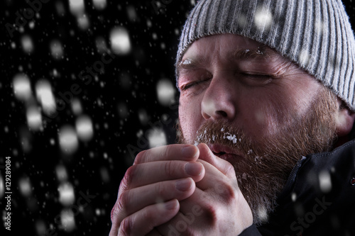 Tableau sur toile Freezing cold man standing in a snow storm blizzard trying to keep warm