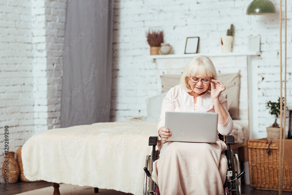 Pleasant disabled aged woman using laptop Pleasant disabled aged woman using laptop