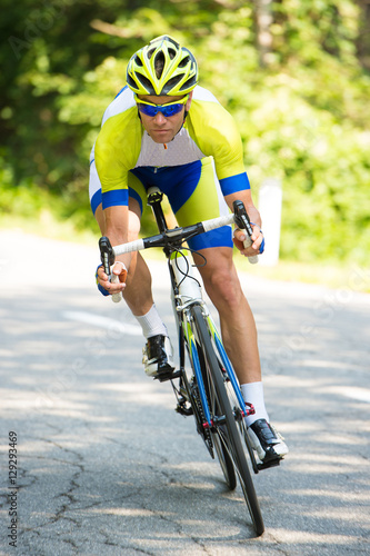 professional sport Cyclist riding a bike on an open road down the hill on a hot summer day