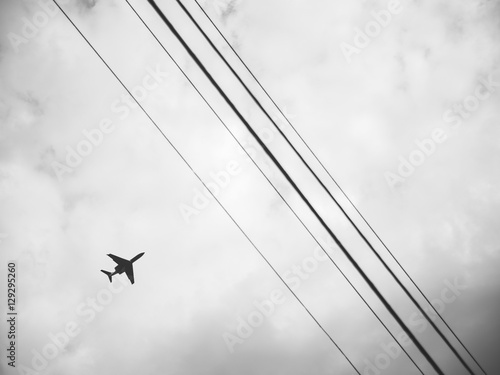 Flugzeug am Himmel mit Stromleitungen