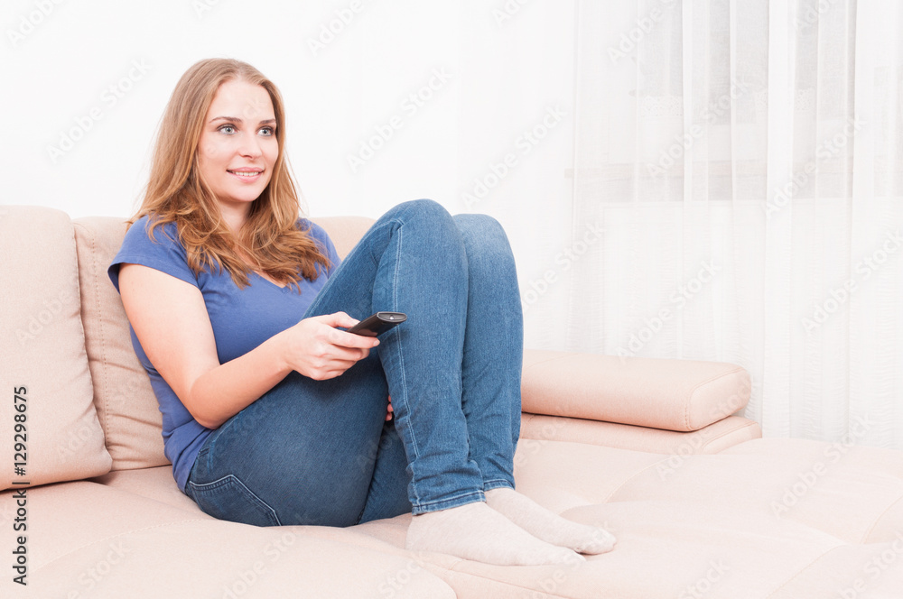 Woman sitting on couch holding remote control Woman sitting on couch holding remote control