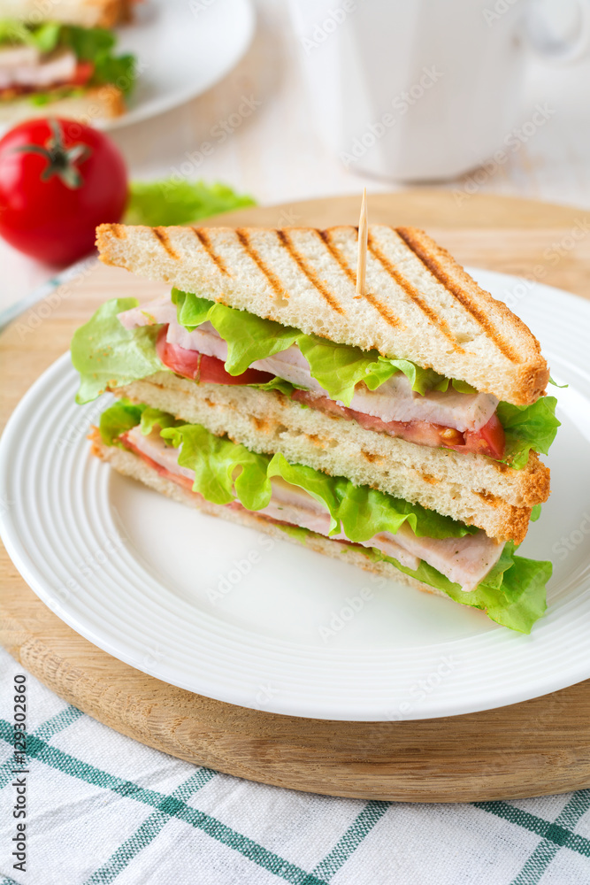Sandwich for breakfast with stuffed tomatoes with ham and lettuce on a light wooden background. Selective focus.