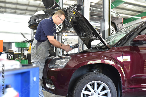 Automotive mechanic with diagnostic computer repaired car in a workshop