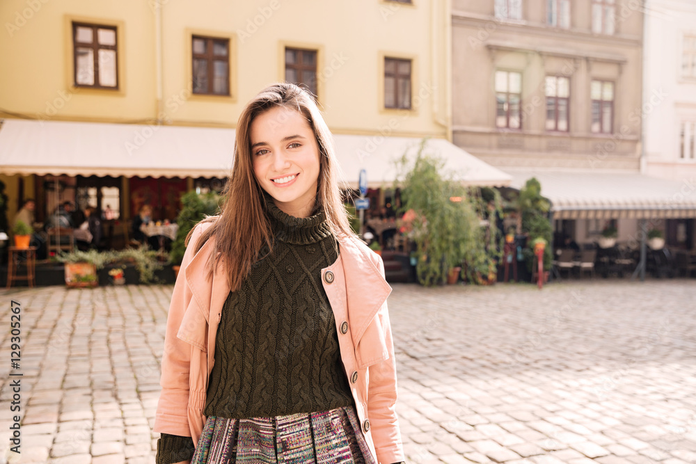 Fototapeta premium Happy woman standing and smiling on the street