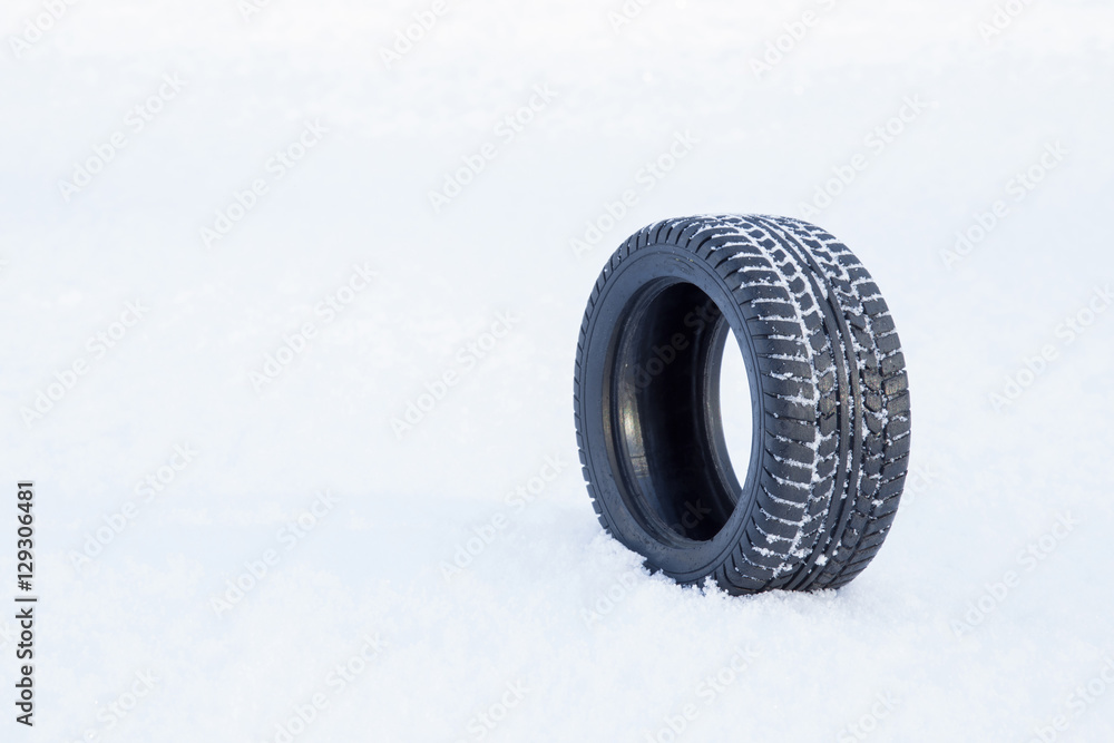 Black rubber tire rolling on the soft, fresh snow in the sunny day. White background. Seasonal tire change. Black rubber tire rolling on the soft, fresh snow in the sunny day. White background. Seasonal tire change.